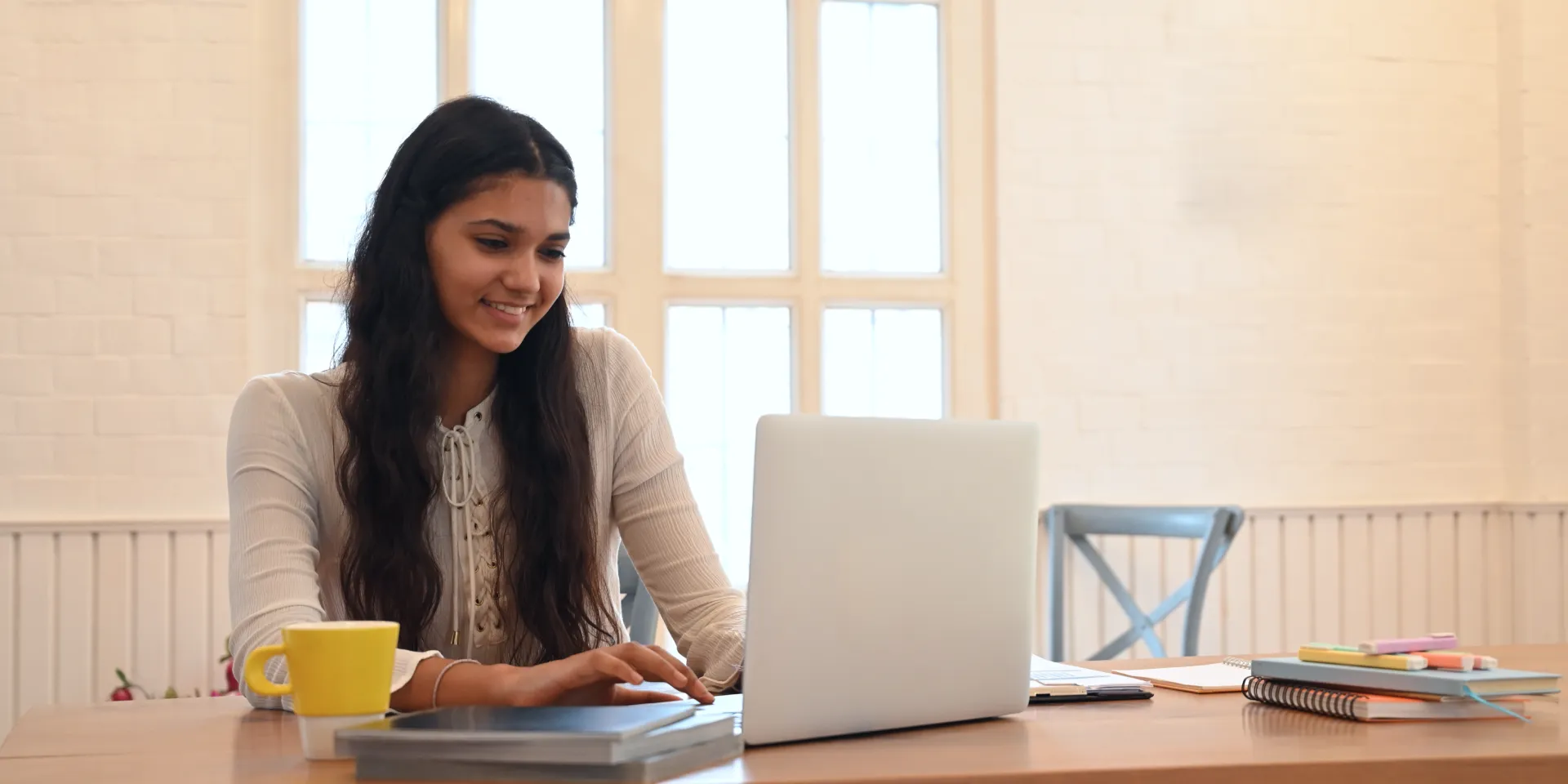 picture of a young Indian girl sitting in front of a laptop and smiling